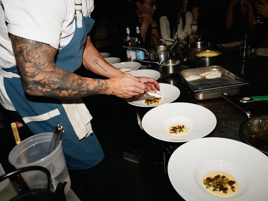 A chef plating a course over white plates at HOT PLATE: Chef Showdown