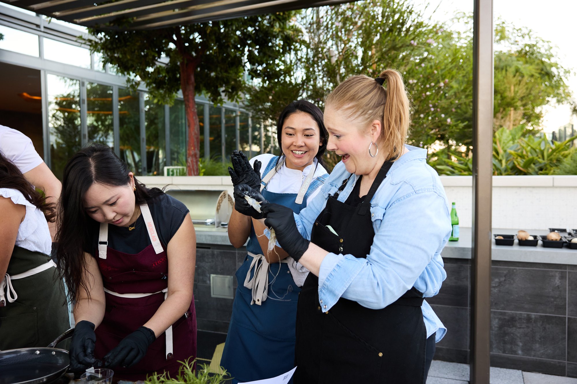 Guests laughing while prepping seafood at a cooking class